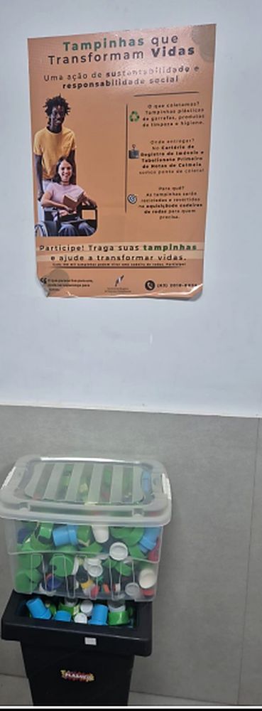 Ponto de coleta de tampinhas plásticas na sede do cartório, com o cartaz da campanha Tampinhas que Transformam Vidas